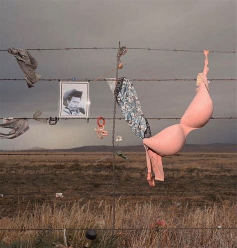 A Naked Woman Hanging Upside Down On A Barbed Wire Fence In The Middle