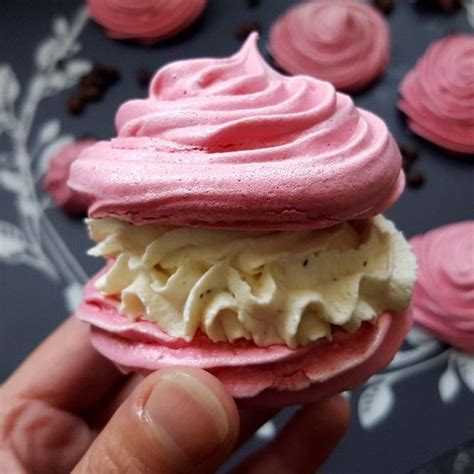 A Hand Holding A Pink And White Cupcake With Icing On It S Side