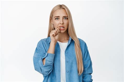 Une Fille Blonde Inquiète Se Mord Le Doigt Et A L air Coupable Devant La Caméra Debout Anxieuse