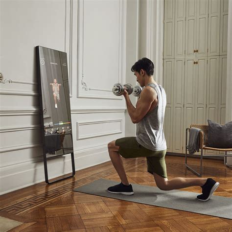 A Man Is Doing Exercises With Dumbbells In Front Of A Mirror And Television