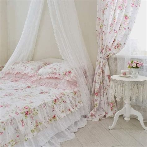 A White Bed Sitting Next To A Window Covered In Pink Flowers On Top Of It