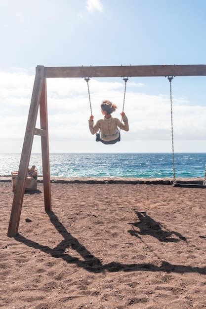 Premium Photo A Woman On Vacation Swinging On A Swing On The Beach Of