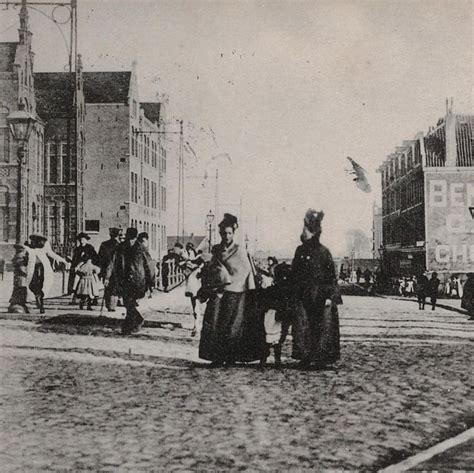 An Old Black And White Photo Of People Walking Down The Street