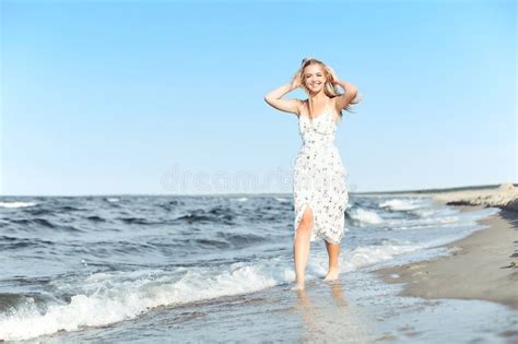 Happy Blonde Beautiful Woman Having Fun On Ocean Beach While Dancing In Waves Stock Photo