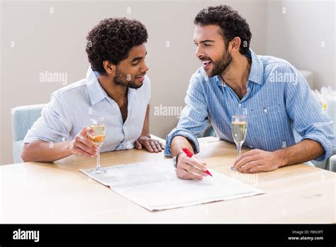 Happy Gay Couple Drinking Champagne And Writing On Newspaper Stock