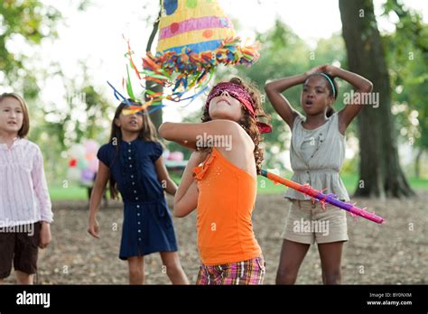 Girl at birthday party hitting pinata Stock Photo - Alamy