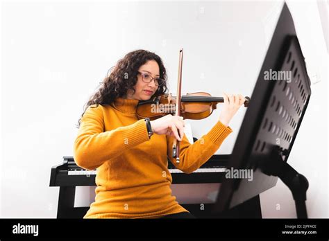 Brunette Woman Wearing A Yellow Sweater And Playing Violin By Reading
