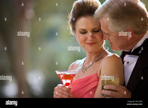 Mature Adult Couple Dressed Formally Showing Affection While Holding Cocktails Stock Photo Alamy