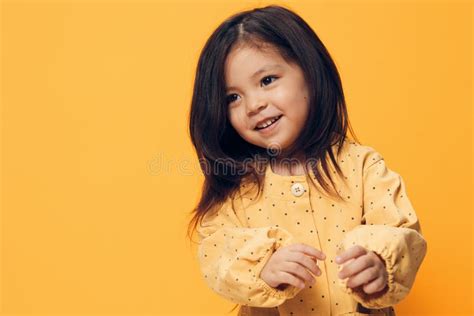 A Beautiful Happy Fashionably Dressed Little Girl Stands On An Orange