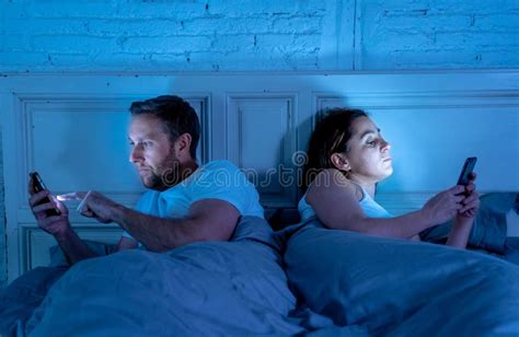 Bored Couple In Bed Addicted To Their Smart Mobile Phones Ignoring Each