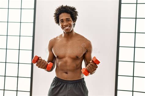 Young African American Man Training Using Dumbbells At Gym Stock Photo