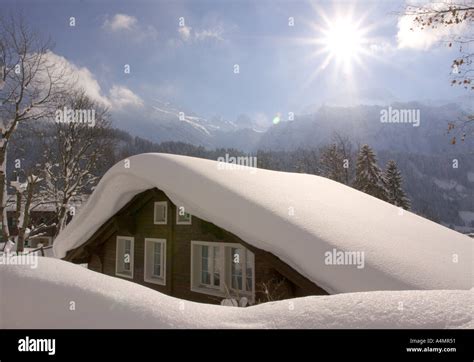 Deep snow on wall and chalet roof glinting in the sunlight from overnight frost at Engelberg in ...