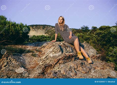 Beautiful Young Blond Woman Sitting On The Background Of Mountains And