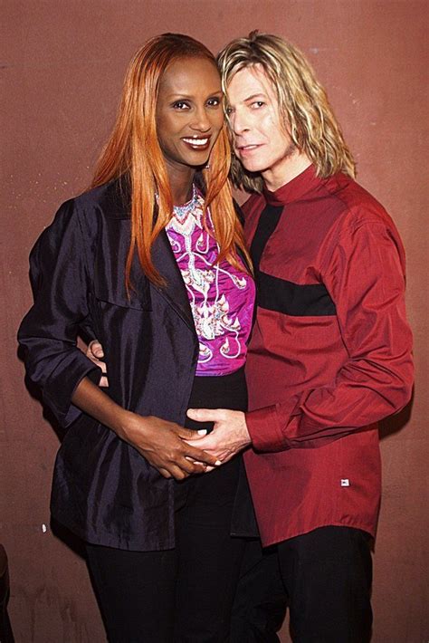 Two Women Standing Next To Each Other In Front Of A Brown Wall And One