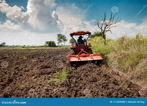 Tractor Para Cultivar El Campo Del Workingon Y El Fondo Del Cielo Foto