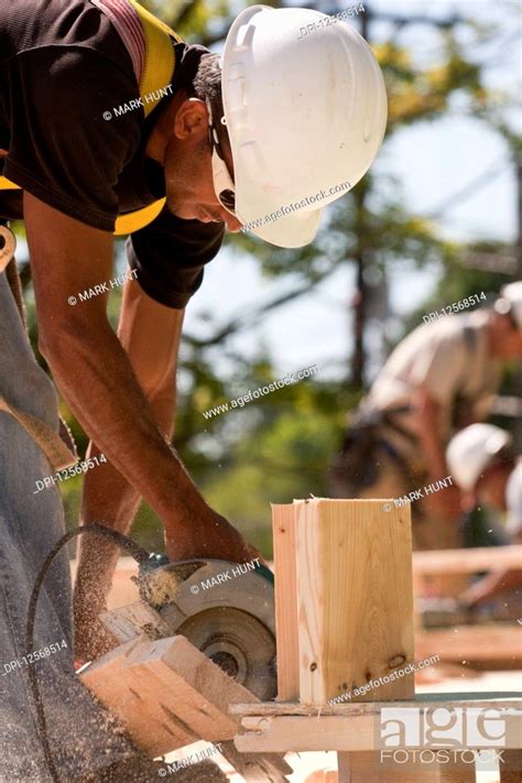 Carpenter Using A Circular Saw At A Construction Site Stock Photo