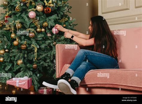 Beautiful Young Brunette Woman On A Sofa Decorates Christmas Tree