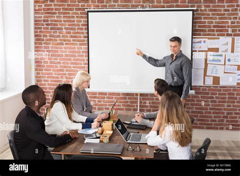 Mature Businessman Giving Presentation To His Colleague In Office