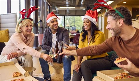 Staff Celebrating At Christmas Party With Meal And Drinks In Office