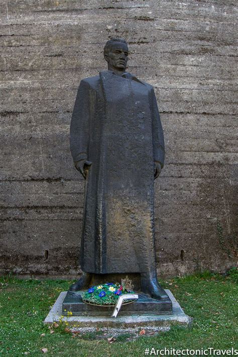 the statue is in front of a stone wall