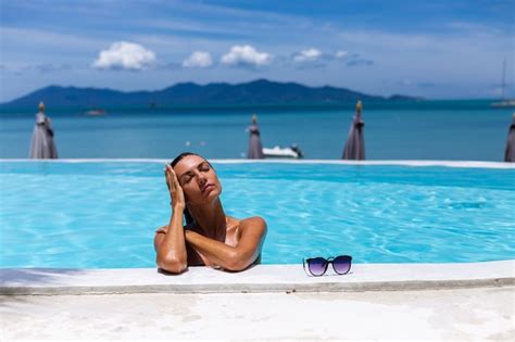 Caucásica mujer bronceada piel de bronce brillante junto a la piscina en bikini azul en un día