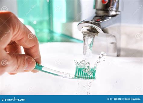 Daily Cleaning Of The Toothbrush After Use In Bathroom Sink Stock Photo