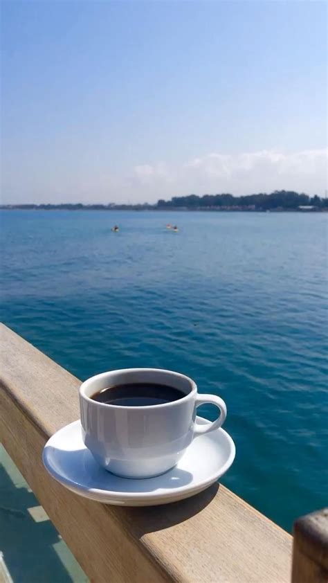 A Cup Of Coffee Sitting On Top Of A White Saucer Next To The Ocean