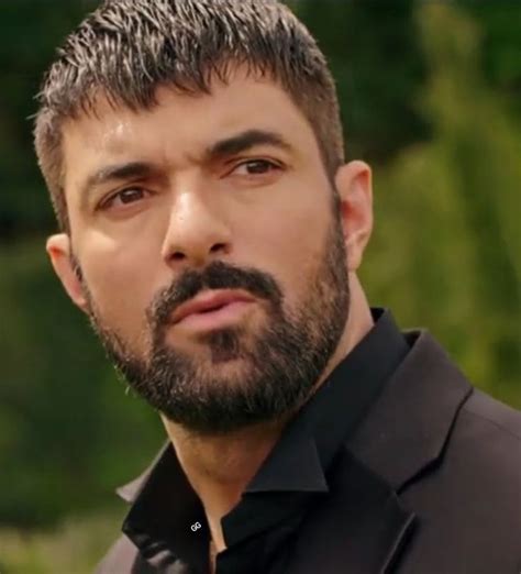 A Close Up Of A Person Wearing A Black Shirt And Beard With Trees In