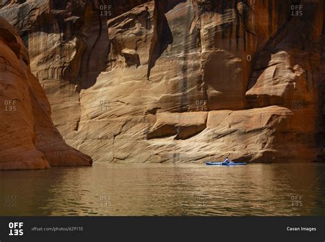 Hiker kayaking on Lake Powell against canyons stock photo - OFFSET