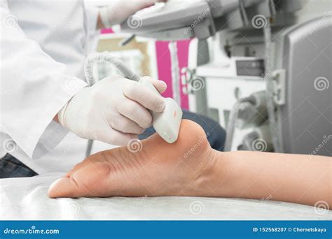 Doctor Conducting Ultrasound Examination Of Patient`s Foot In Clinic