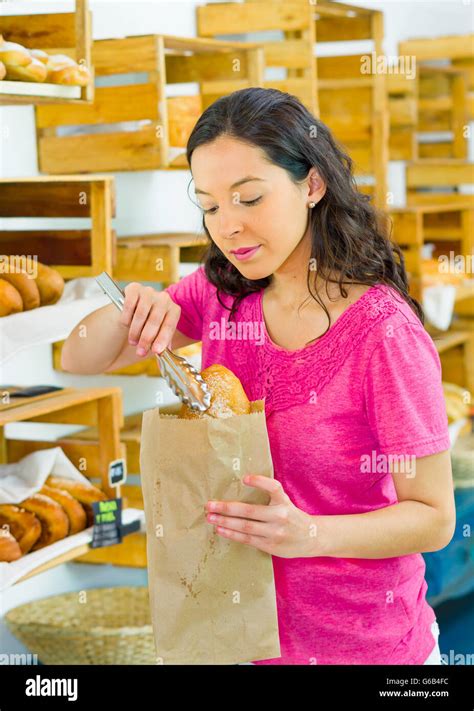 Pretty Brunette Wearing Pink Shirt Placing Bread Inside Brown Paper Bag