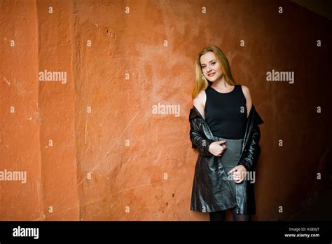 Blonde Fashionable Girl In Long Black Leather Coat Posed Near Street