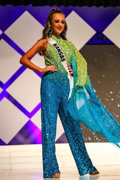 A Beautiful Woman Standing On Top Of A Stage Wearing A Blue And Green