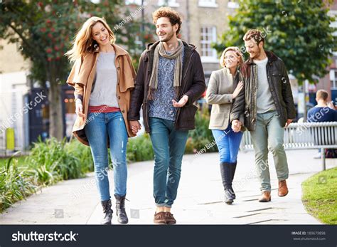 Group Friends Walking Through City Park Stock Photo