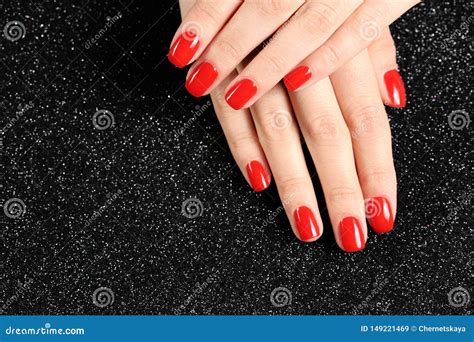 Woman Showing Manicured Hands With Red Nail Polish On Black Background