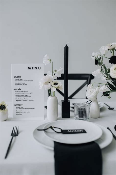 A White Table Setting With Flowers And Menu