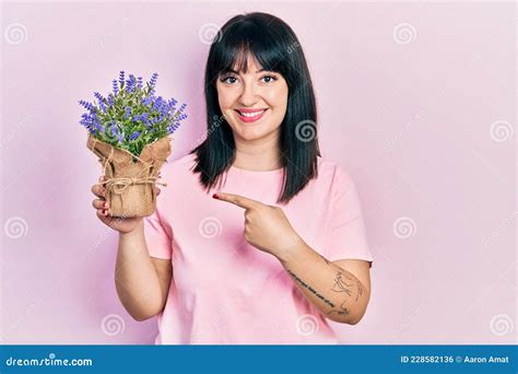 Young Hispanic Woman Holding Lavender Plant Smiling Happy Pointing With