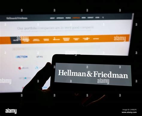 Person Holding Cellphone With Logo Of American Private Equity Company Hellman And Friedman Llc