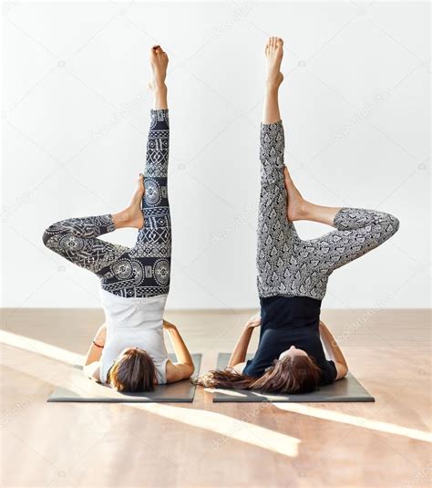 Two young women doing yoga asana supported shoulderstand Stock Photo by ©Gladkov 116688926