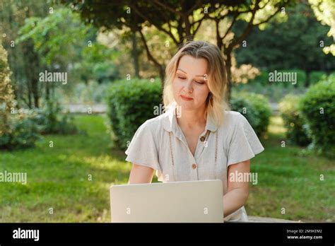 A Beautiful Mature Woman In Glasses Works On A Computer At A White