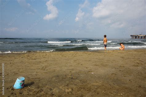 Boy And Girl Peeing Side By Side On The Beach Looking At The Sea Stock