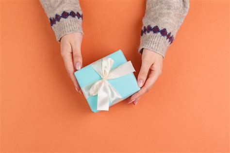 Premium Photo Woman Hands Holding Gift Box On Orange