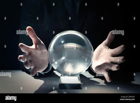 Businessman Using Crystal Ball To Predict Future At Table In Darkness