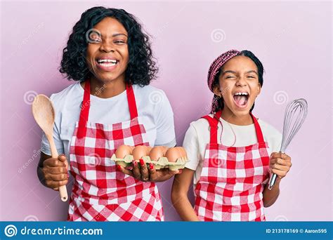 Beautiful African American Mother And Daughter Cooking Cake Using Baker Whisk Smiling And