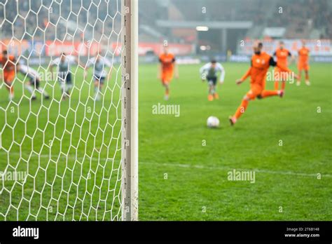 Detail of goal's post with net and football player during penalty kick ...