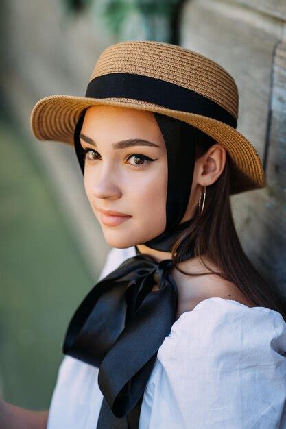 Un gran retrato de una niña en un sombrero de paja y con cintas negras