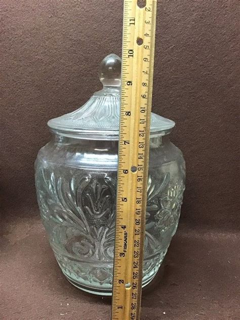 A Glass Jar With A Measuring Tape Next To It