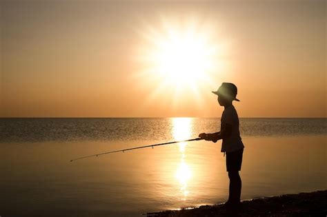 Un niño pescador feliz pescando en el mar en el viaje de silueta de la