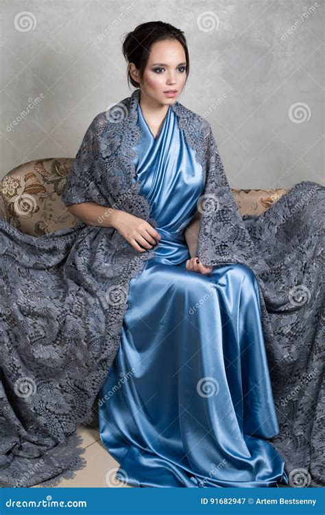 Junger Brunette In Einem Blauen Seidenkleid Und Spitze Langen Kap Sitzt