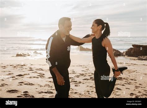 Positive Mature European Man And Woman Doing Leg Exercises Stretching